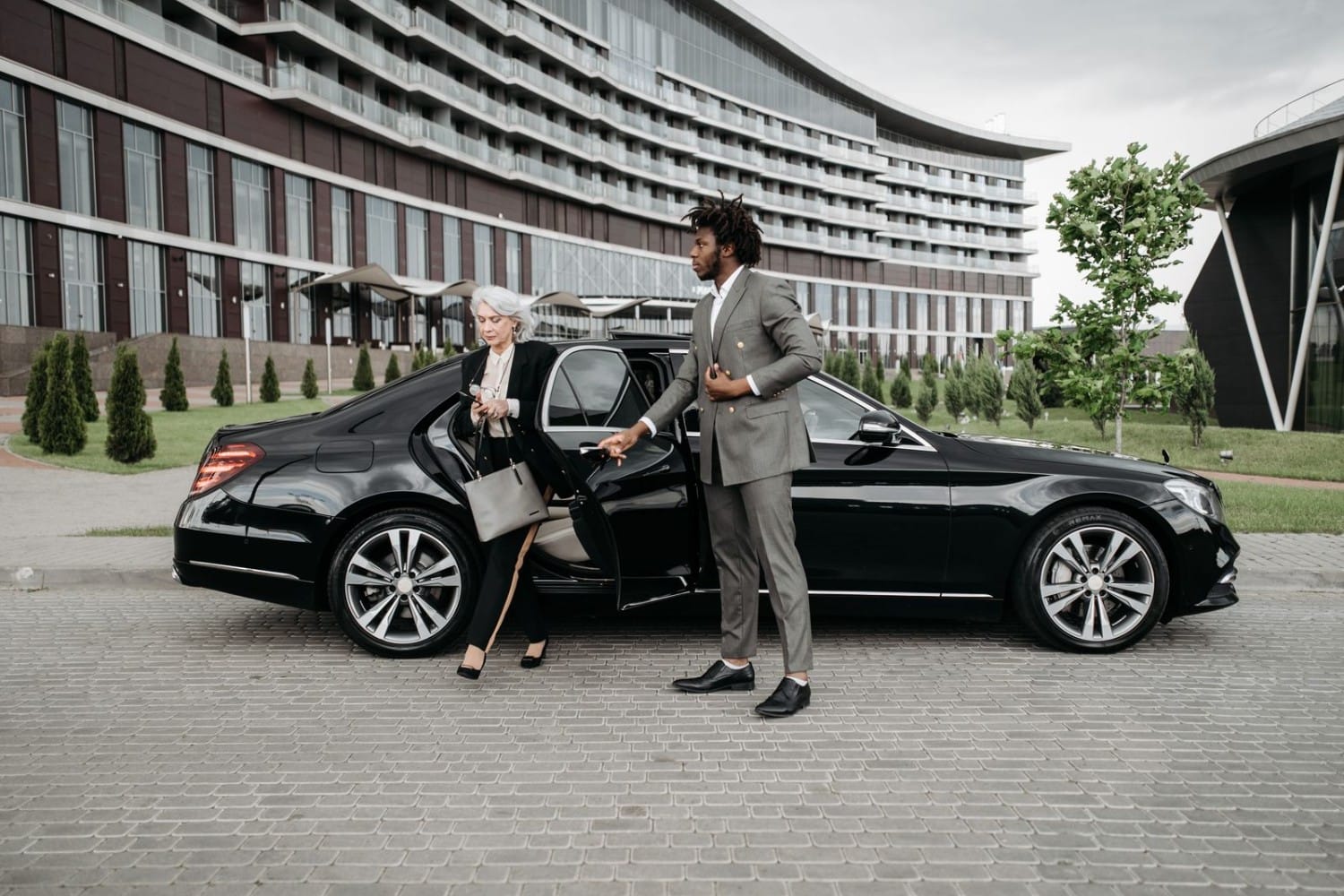 Chauffeur assisting a business executive out of a luxury car